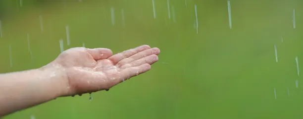 Mano comprobando como llueve desde dentro de un edificio